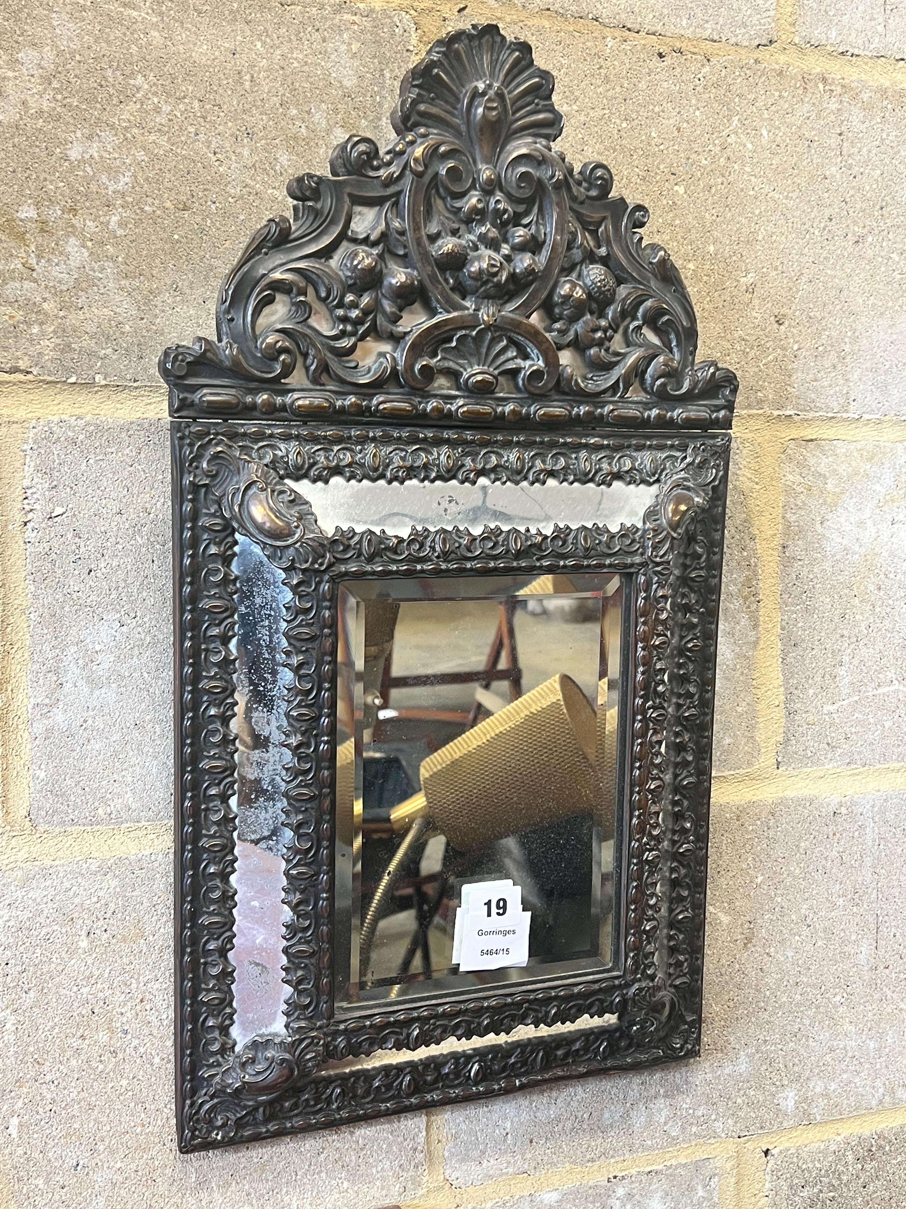A Dutch brass framed cushion wall mirror, with ornate arched cresting, pierced and repousse with birds, scrollwork and shell surmount, width 33cm height 58cm